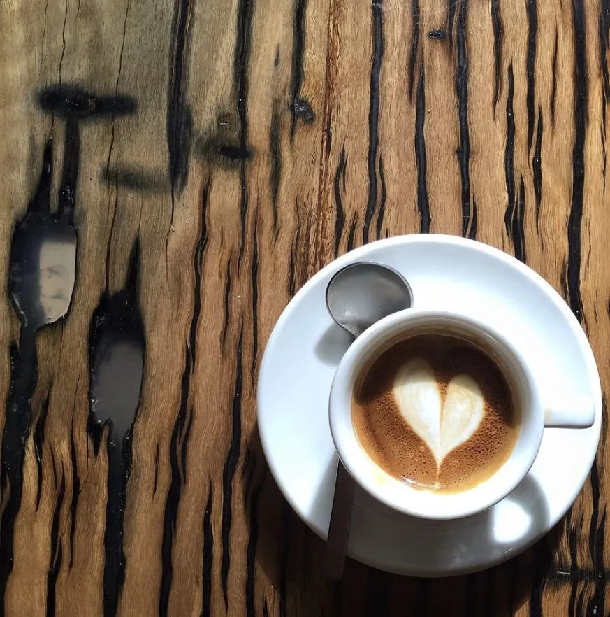 Flat white with latte art on a timber bench